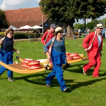 Groep deelnemers draagt samen bollen kaas tijdens een speelse buitenactiviteit op Parkhoeve De Middelt.