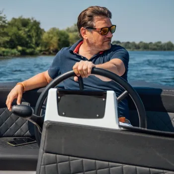 Man stuurt een sloep over de Maasplassen en geniet van een zonnige dag op het water.