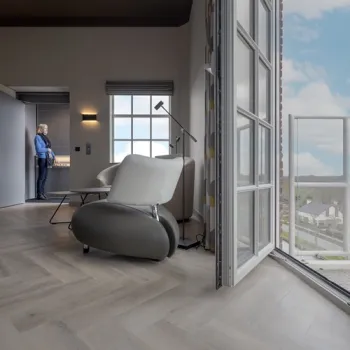 Interieur van Bed & Breakfast Mouttoren Weert met zithoek, grote ramen en uitzicht over de stad vanaf het balkon.