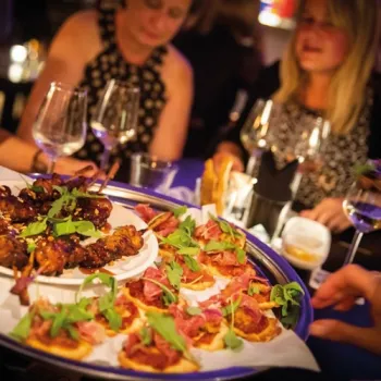 Gasten genieten van shared dining met kleine gerechten en een goed glas wijn in de sfeervolle ambiance van De SooS in Weert.